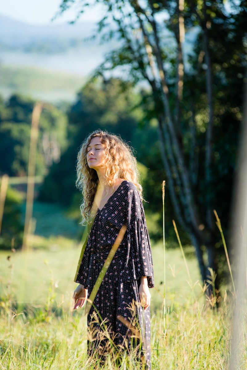 photo of woman looking up the trees