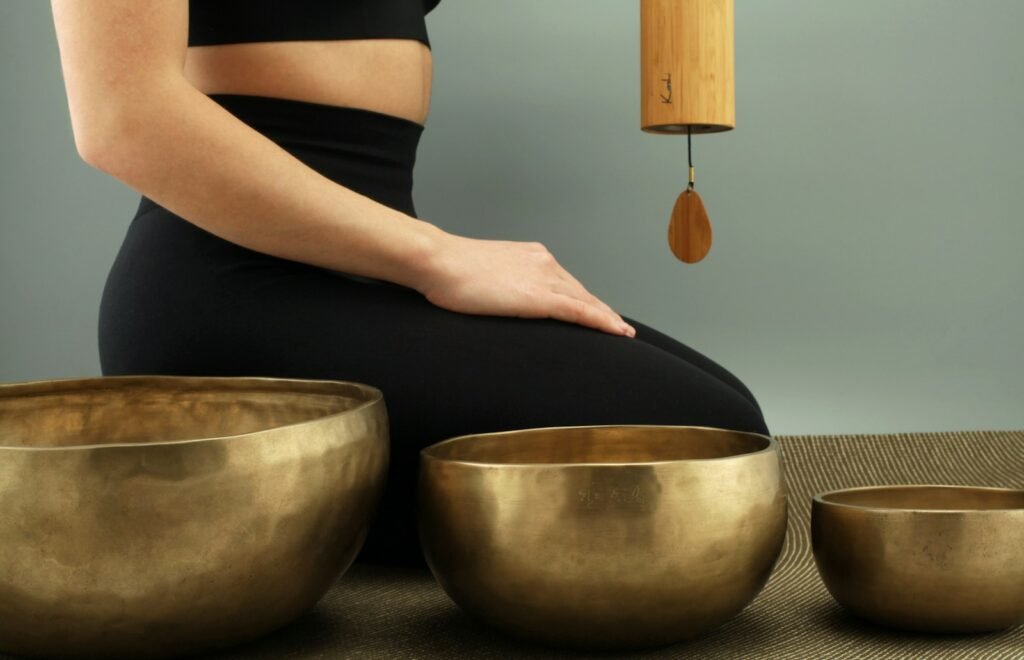 woman kneeling beside three brass-colored bowls