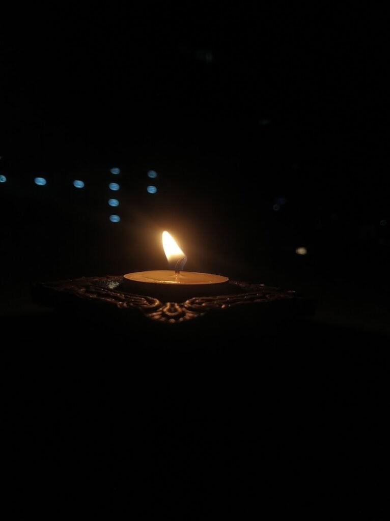 A single candle flame glows in the dark.